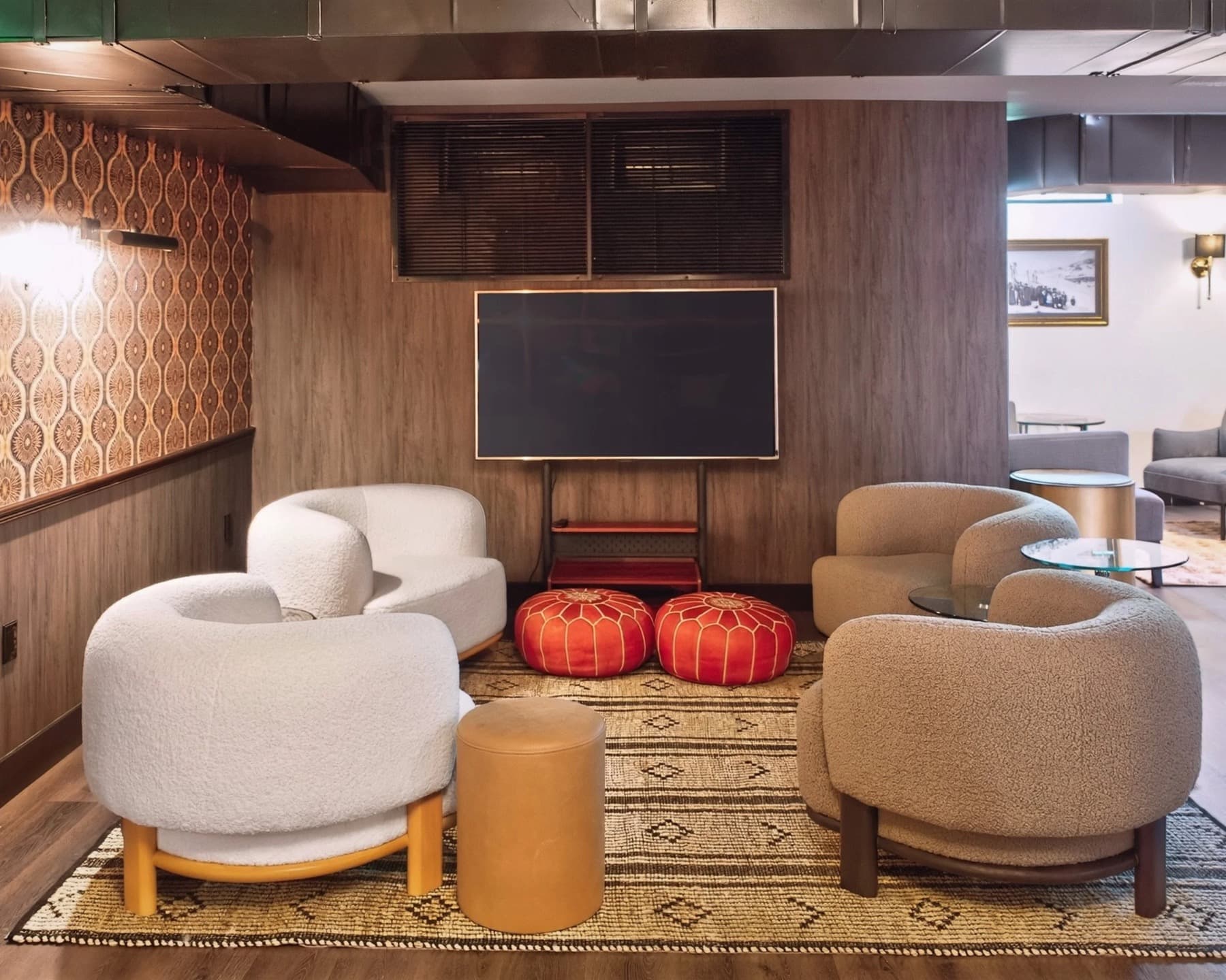 A cozy lounge nook at The Grove with boucle chairs and a shared television